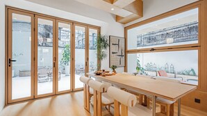 A modern dining area with a wooden table and chairs, large windows, and a view of the cityscape. - Cheens Hotel (Chengdu)