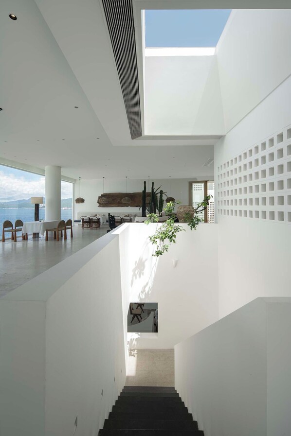 A spacious interior with a staircase leading to a lower level, a dining area with chairs and a table, and a view of the sea. - Shenzhen Secret Wild Reef Beautiful Stay (Shenzhen)