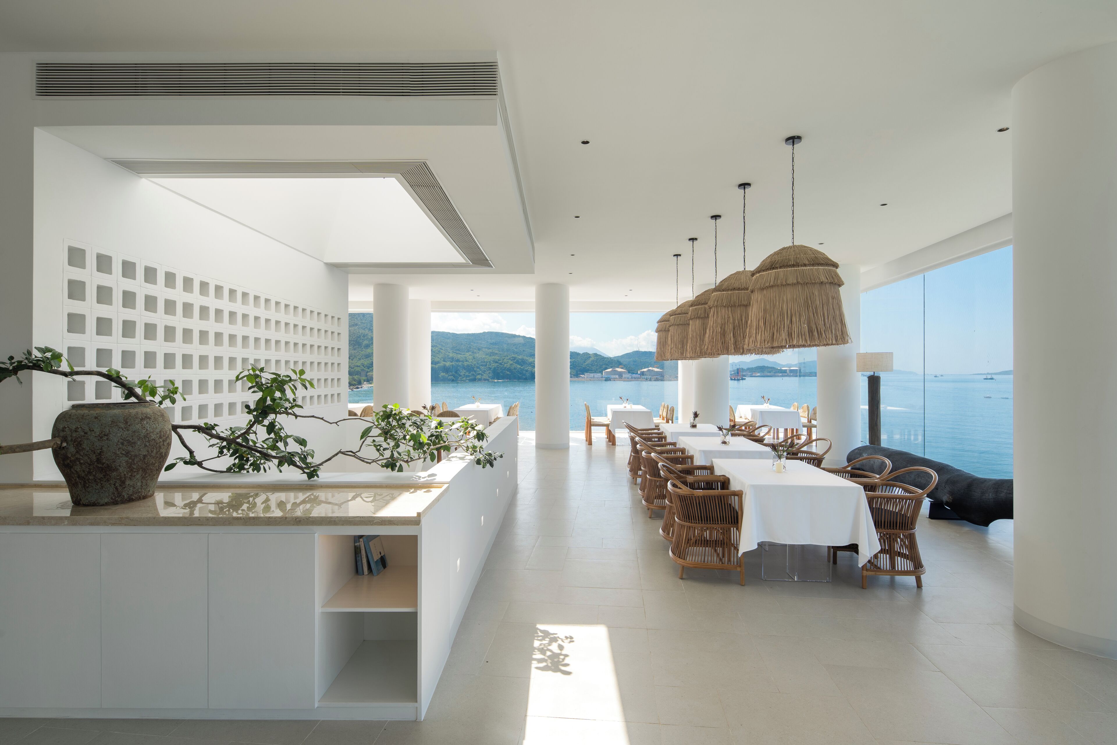 A modern dining area with a view of the sea, white walls, and natural light.