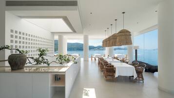 A modern dining area with a view of the sea, white walls, and natural light.