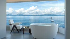 A modern bathroom with a large bathtub, a white chair, and a small table with books and lemons. - Shenzhen Secret Wild Reef Beautiful Stay (Shenzhen)