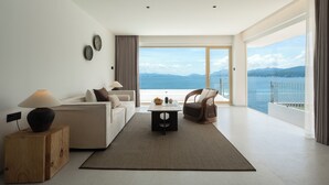 A modern living room with a sofa, a coffee table, and a chair. There is a view of the sea through large windows. - Shenzhen Secret Wild Reef Beautiful Stay (Shenzhen)