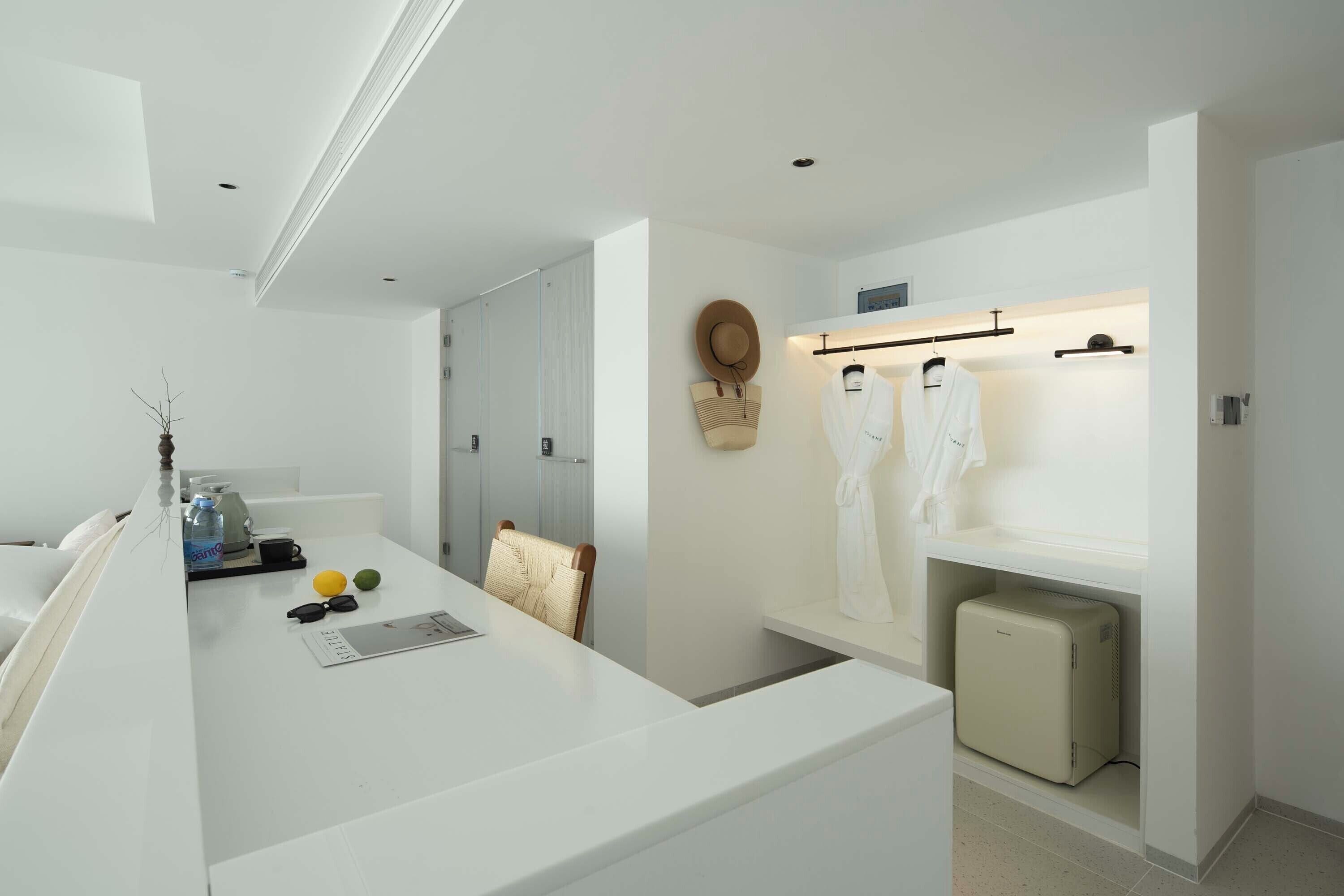 Un baño moderno y minimalista con un tocador blanco, un perchero y un pequeño mueble de almacenamiento.