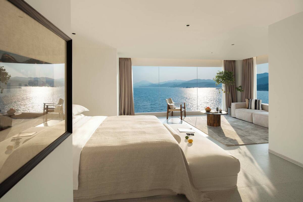 Una moderna camera d'albergo con un letto grande, un divano, un tavolino e vista sul mare.