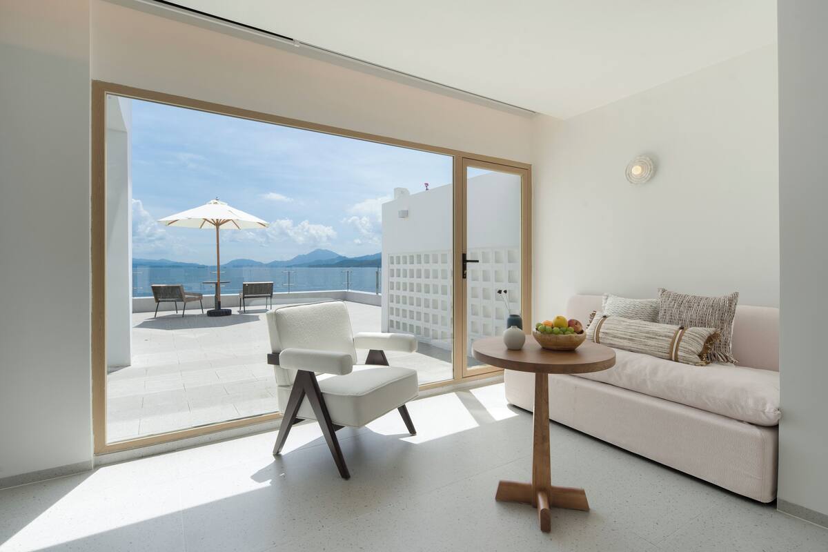 Un soggiorno moderno con un divano, un tavolino rotondo e vista su una terrazza con mobili da esterno.