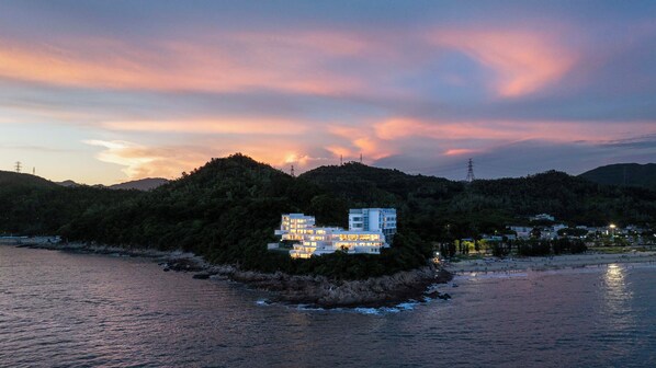 A coastal property with multiple buildings, a beach, and a forested hill. - Shenzhen Secret Wild Reef Beautiful Stay (Shenzhen)