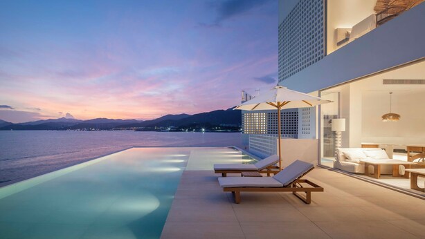A modern hotel with a pool, lounge chairs, and a view of the sea at sunset. - Shenzhen Secret Wild Reef Beautiful Stay (Shenzhen)