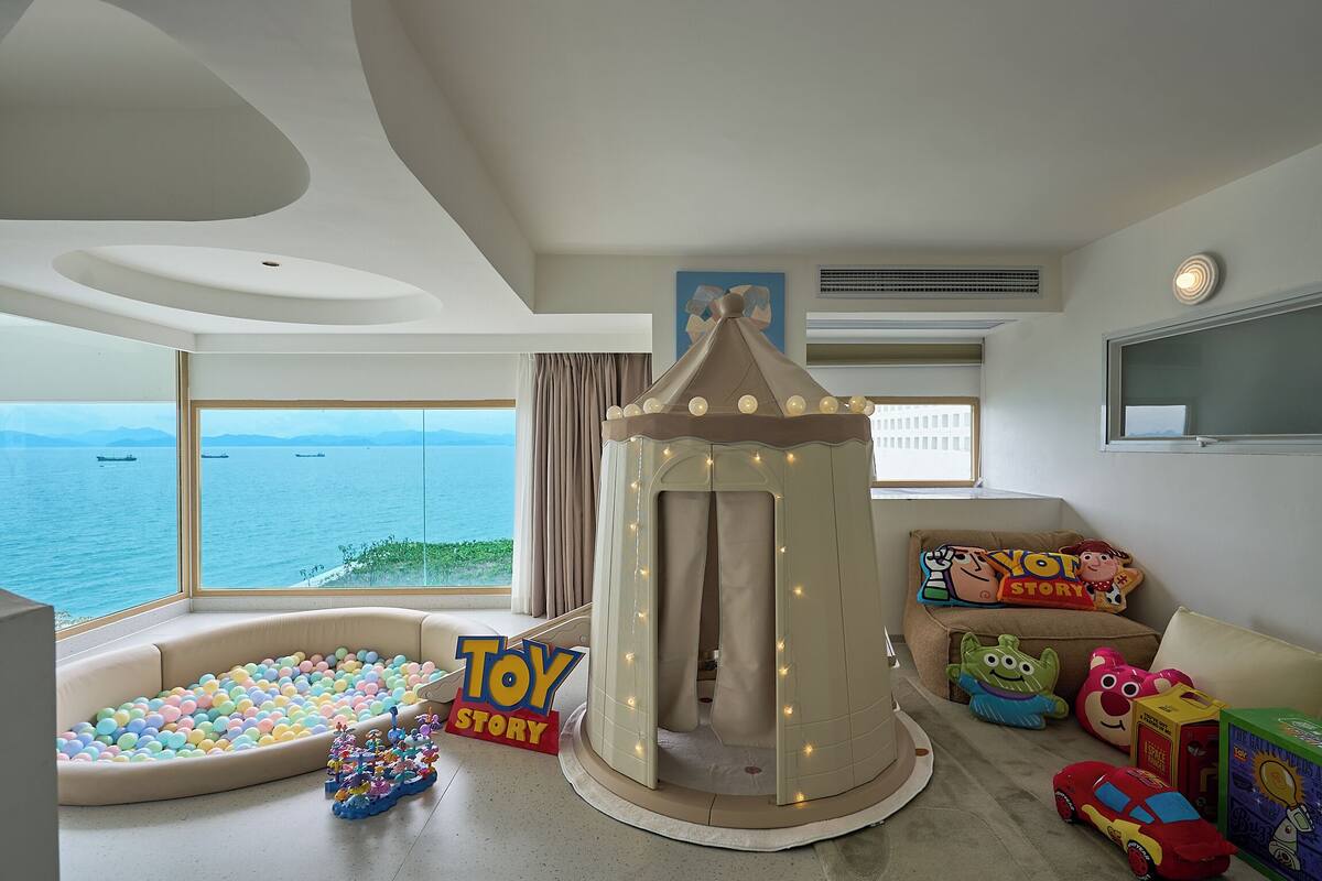 Un'area giochi per bambini con una piscina di palline, una tenda illuminata e giochi.