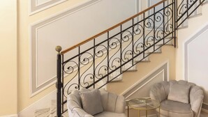 A staircase with ornate black railings and a marble floor. There are two grey armchairs and a small round table with a glass top. - Hotiday Room Collection - Rapallo (Rapallo)