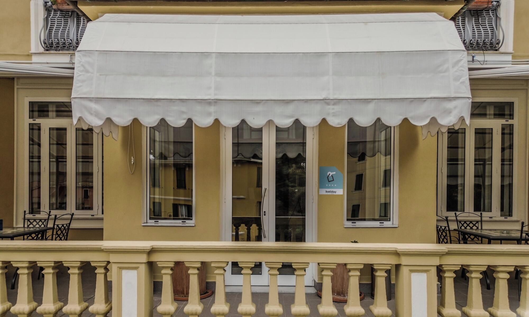 A building with a white awning, a balcony with a balustrade, and a sign indicating a holiday rate.