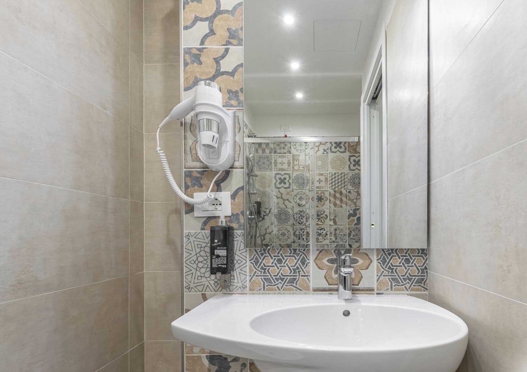 A bathroom with a white sink, a hairdryer, and a mirror.