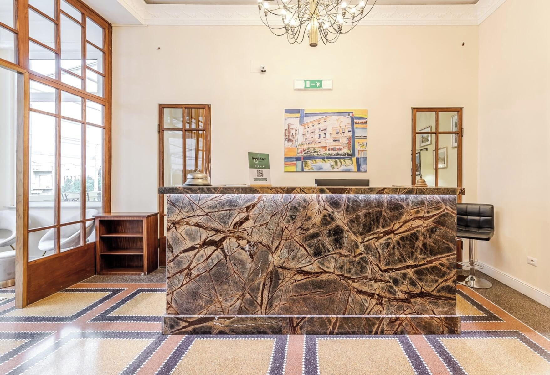 A reception area with a marble counter, a chandelier, and a painting on the wall.