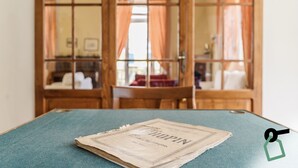 Une pièce avec une porte en bois, une table bleue et un journal posé sur la table.
