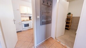 Una cocina con armarios blancos, una estufa y un estante de madera montado en la pared.