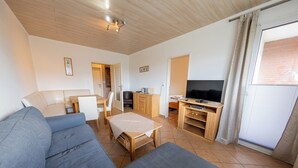 Una sala de estar con sofá, televisor y mueble de madera.