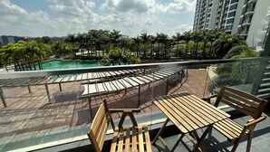A rooftop terrace with wooden seating, a swimming pool, and a view of a cityscape. - Green Haven Comfort House (Masai)