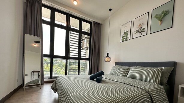 A bedroom with a large window, a bed with checkered bedding, a bedside table, and a hanging light fixture. - Green Haven Comfort House (Masai)