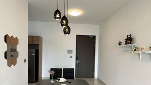 A modern dining area with a dark table, white walls, and a geometric wall decoration. - Green Haven Comfort House (Masai)
