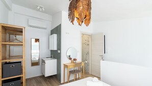 Ein modernes Hotelzimmer mit einem Bett, einem Holzschrank, einem Badezimmer inklusive Spiegel und Dusche.