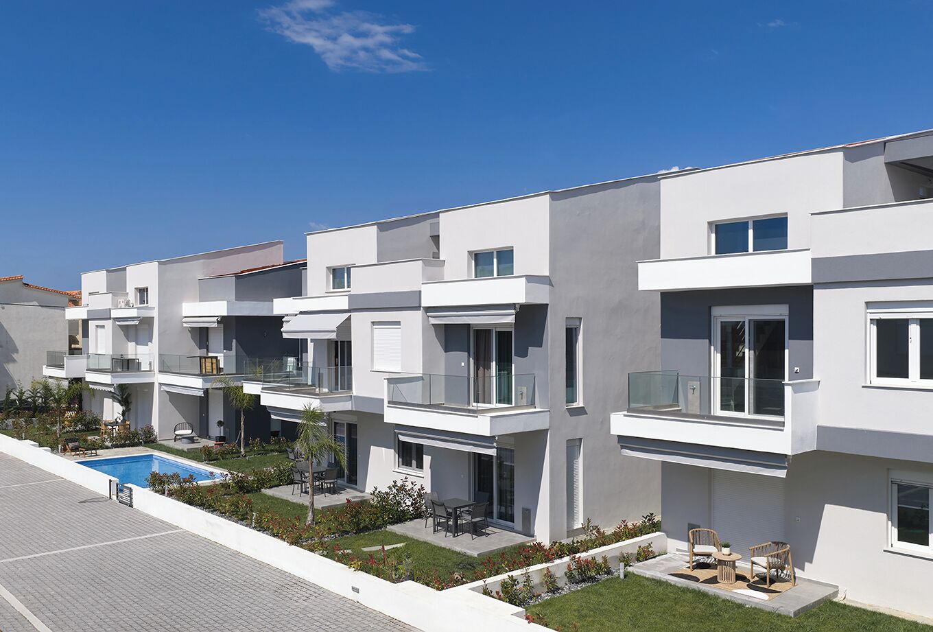 Um edifício residencial moderno, com várias andares, varandas, piscina e um jardim ajardinado.