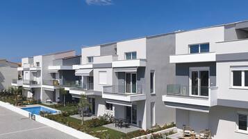 Um edifício residencial moderno, com várias andares, varandas, piscina e um jardim ajardinado.
