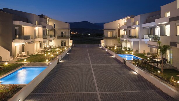 Ein modernes Hotel mit zentralem Pool, Sitzgelegenheiten im Freien und einer Bergkulisse.