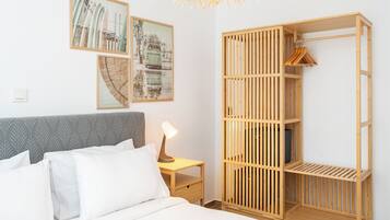 A bedroom with a bed, a bedside table with a lamp, a wardrobe, and wall art.