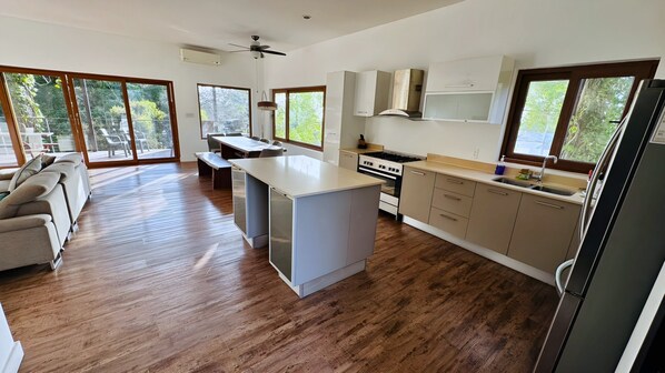 A modern kitchen with a central island, wooden flooring, and large windows. - Gemini Villas Gemini II (Saboga)