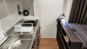 Una kitchenette compacta con estufa, lavamanos y un mueble pequeño.