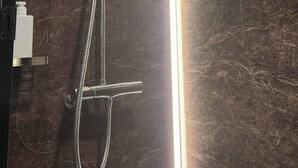 Una ducha moderna con cabezal de ducha de mano y grifo empotrado.