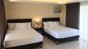 A hotel room with two beds, a nightstand with a lamp, an air conditioning unit, and a window with curtains. - Papakit's Marina and Fishing Lagoon powered by Cocotel (Liloan)