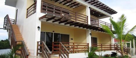 Una casa de dos pisos con balcón, escalera y piscina.
