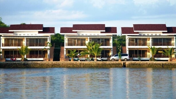 A row of modern, two-story buildings with balconies, situated by a calm body of water. - Papakit's Marina and Fishing Lagoon powered by Cocotel (Liloan)