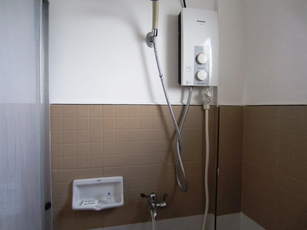 A bathroom with a shower, a toilet, and a soap dispenser.