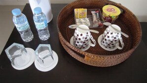 A table with a water bottle, a cup, a napkin holder, a tissue roll, a box of tissues, a cup of coffee, a cup of tea, and a basket with a spoon and a napkin. - Papakit's Marina and Fishing Lagoon powered by Cocotel (Liloan)