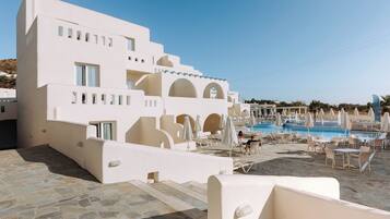A modern hotel with a pool area, outdoor seating, and a clear view of the surrounding landscape.