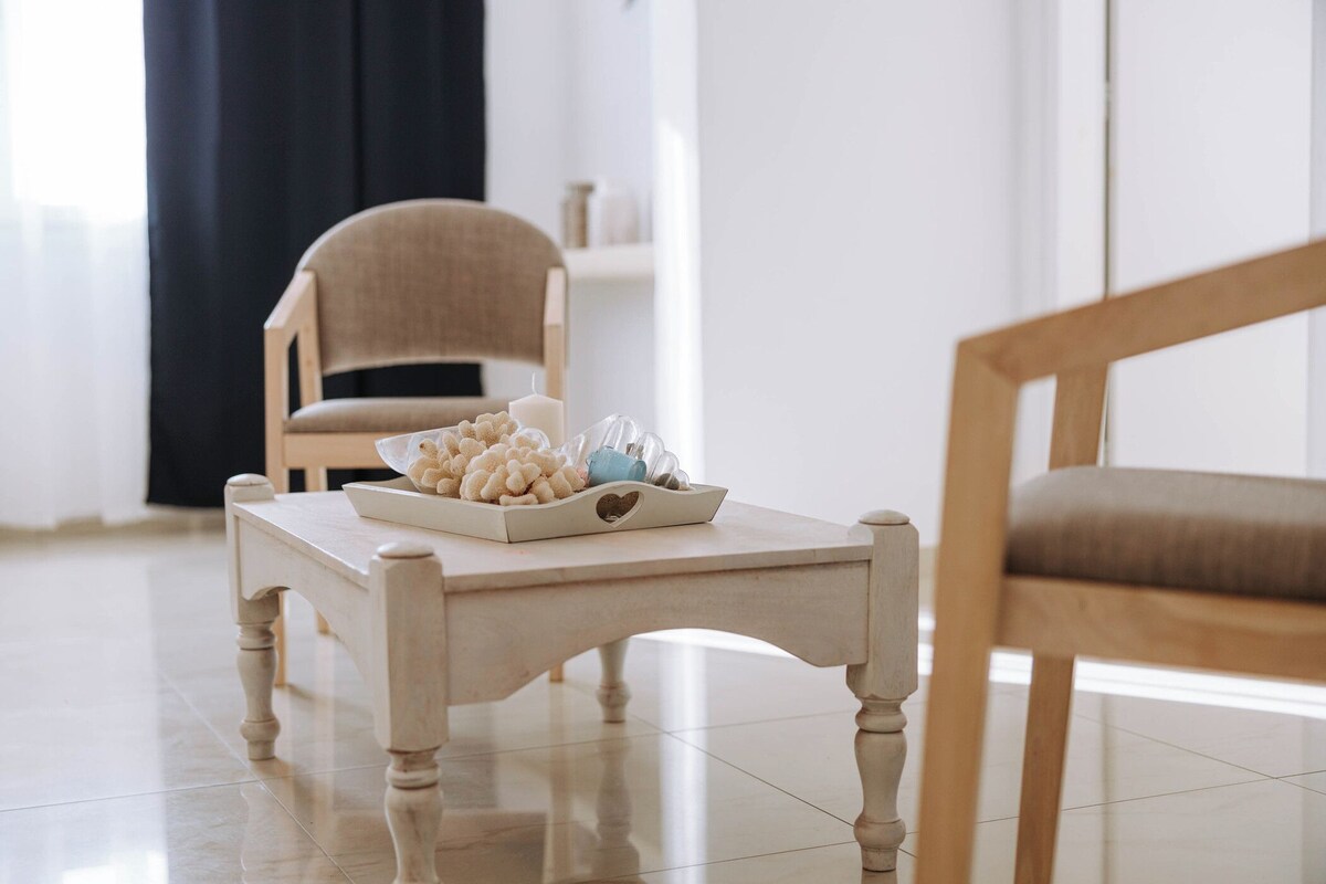 A room with a wooden coffee table, a chair, and a decorative bowl on the table.