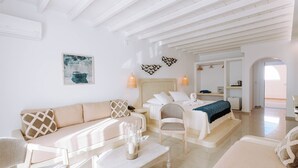 A modern, well-lit room with a sofa, a chair, a bed, and a small table with decorative items. - Hotiday Room Collection - Naxos (Naxos)