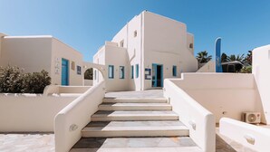 A white building with blue accents and a stone staircase leading to a door. - Hotiday Room Collection - Naxos (Naxos)
