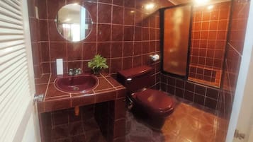 Een badkamer met een ronde spiegel, een wastafel, toilet en een douchehoek.
