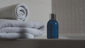 A bathroom with a rolled white towel and a blue bottle on a sink. - Hotel New Jatrabari (Dhaka)