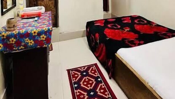 A small, well-lit room with a bed, a desk with a computer, a television mounted on the wall, and a ceiling fan. - Hotel New Jatrabari (Dhaka)