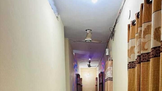 A narrow hallway with potted plants on one side and patterned curtains on the other. - Hotel New Jatrabari (Dhaka)