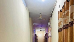 A narrow hallway with potted plants on one side and patterned curtains on the other. - Hotel New Jatrabari (Dhaka)