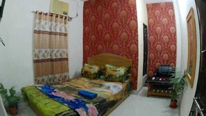 A bedroom with a bed, a ceiling fan, a desk with a chair, and a potted plant. - Hotel New Jatrabari (Dhaka)