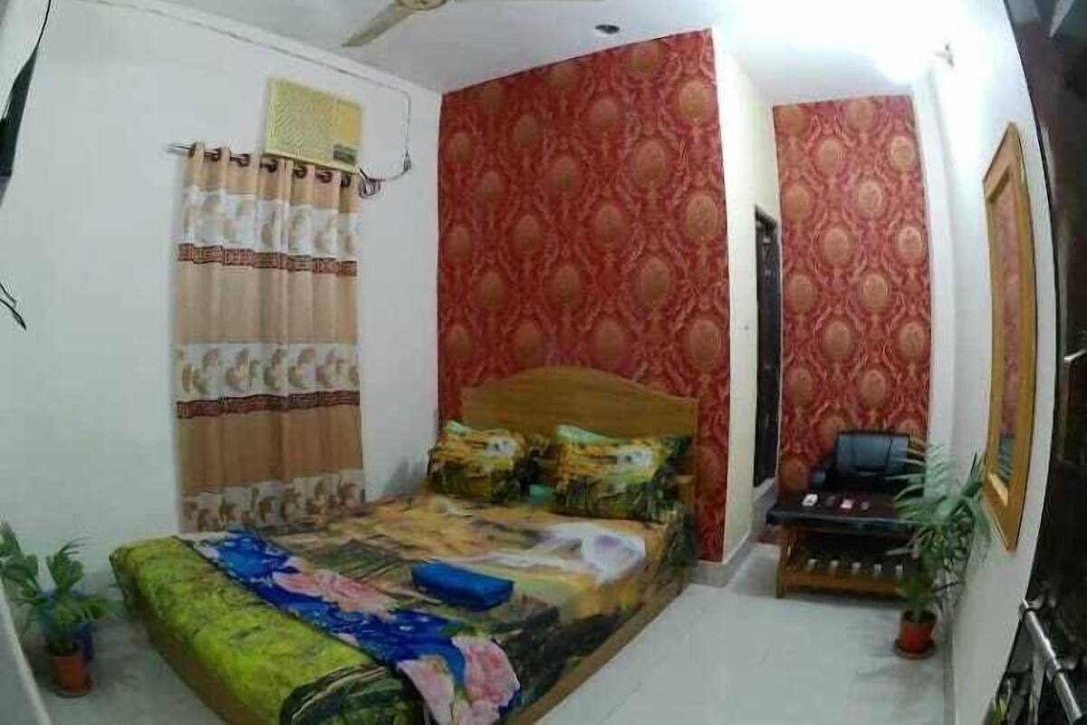 A bedroom with a bed, a ceiling fan, a desk with a chair, and a potted plant.