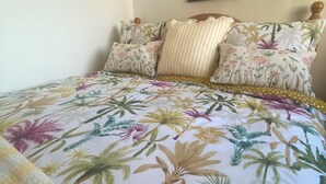 A bed with floral and tropical print bedspread, wooden headboard, and decorative pillows. - Cosy Irish Cabin studio in fabulous Derry with WiFi & Private Bathroom (Derry)