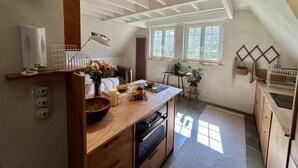 A kitchen with a wooden countertop, a sink, and a window with a view of greenery. - Le Nid des Falaises, au bord de la plage (Varengeville-sur-Mer)