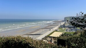 A coastal view with a beach, promenade, and buildings along the shore. - Le Nid des Falaises, au bord de la plage (Varengeville-sur-Mer)