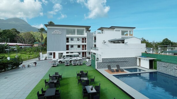 A modern hotel with a pool, outdoor seating, and a mountain view.